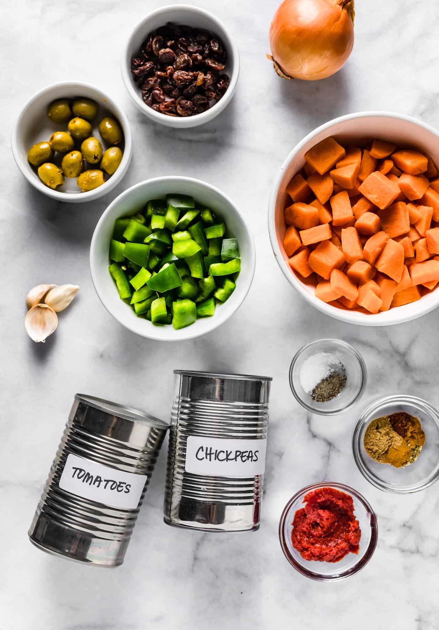 Vegetarian sweet potato picadillo ingredients on a white marble countertop.