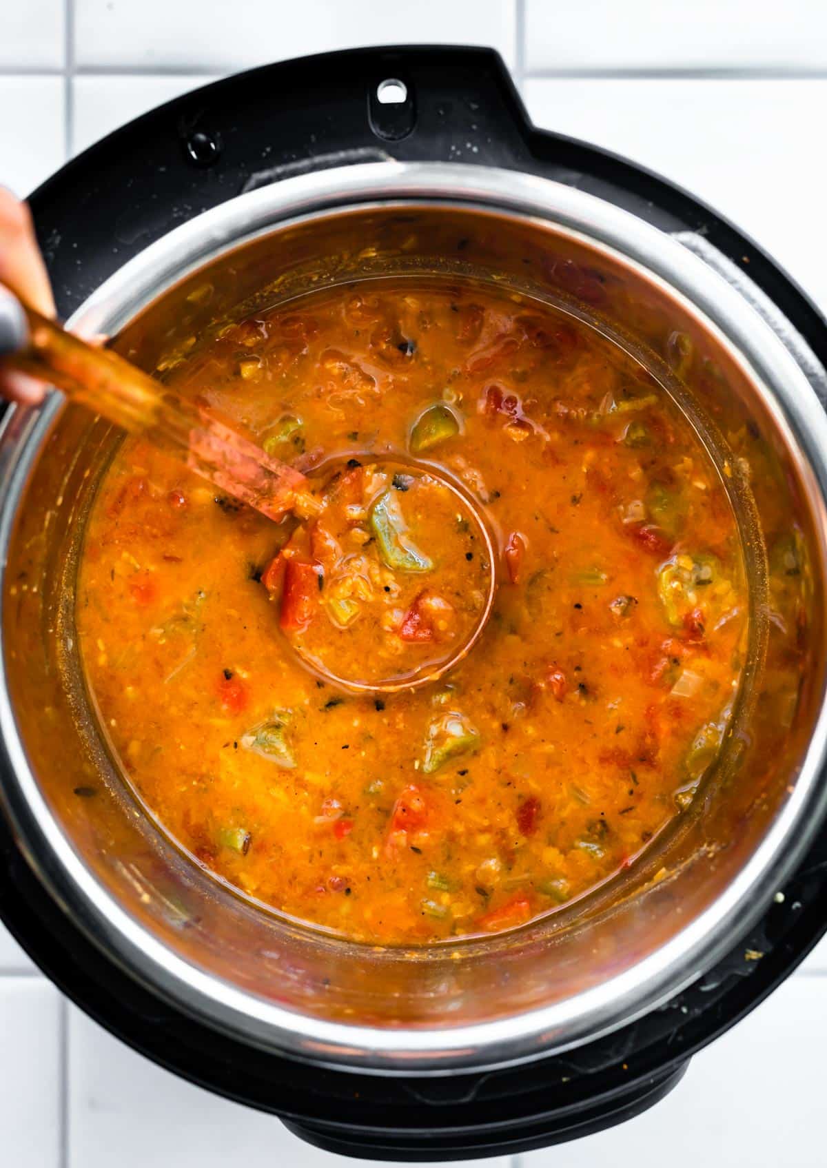 Overhead shot of ladle scooping up finished Instant Pot Gumbo after roux is added.