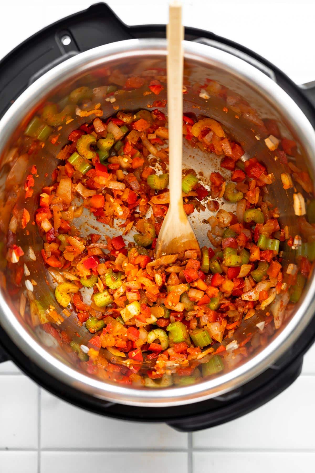 Overhead shot of sautéd onion, garlic, bell peppers and celery in a instant pot.