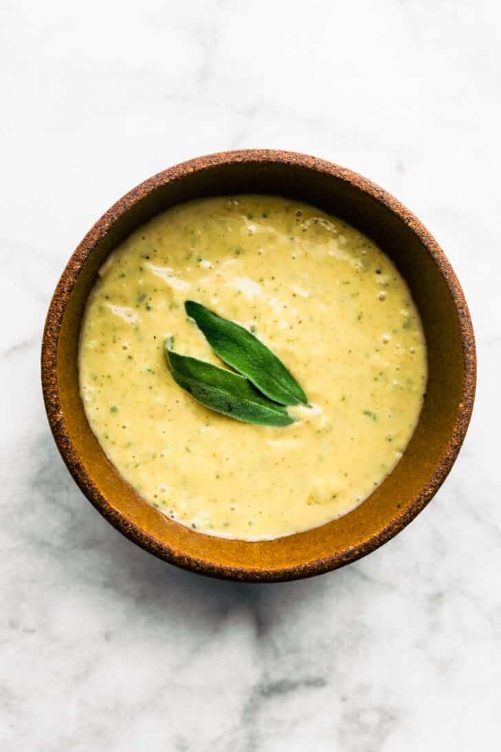 Lemon sage sauce in a wooden bowl topped with fresh sage.