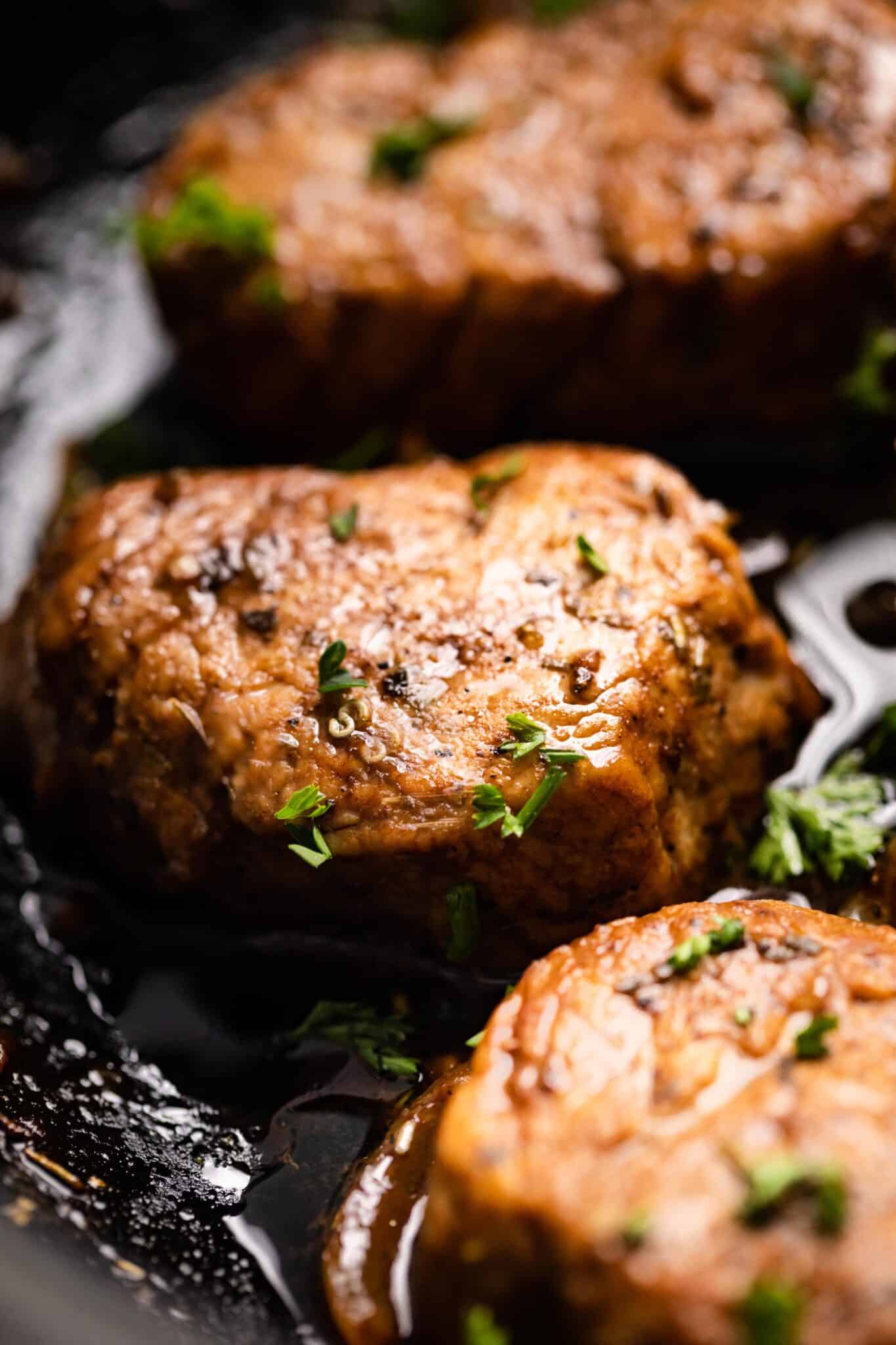 Up close photo of seared Mediterranean pork medallions garnished with parsley.