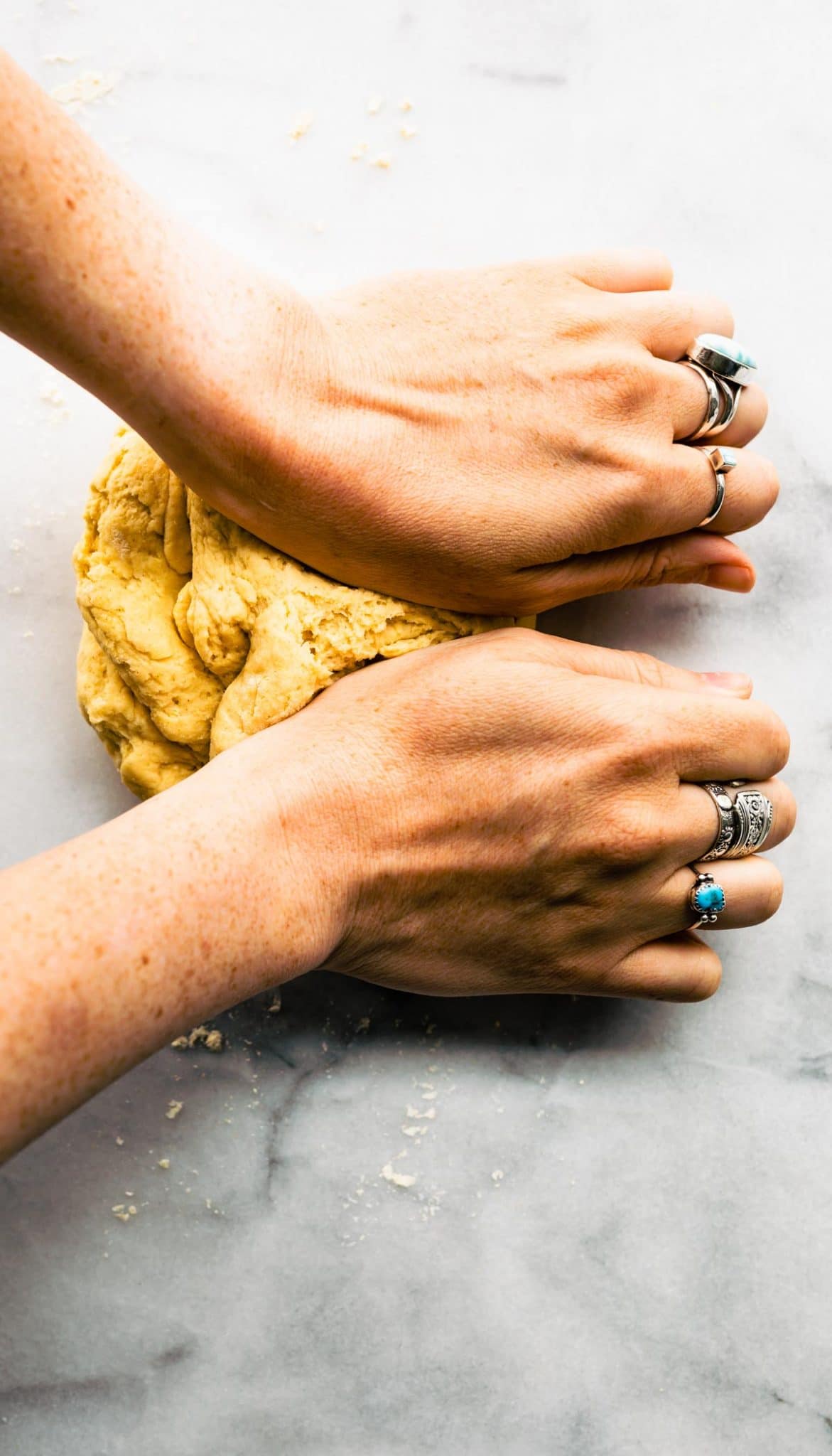 A woman's hands kneading yeast free pizza dough on a countertop.
