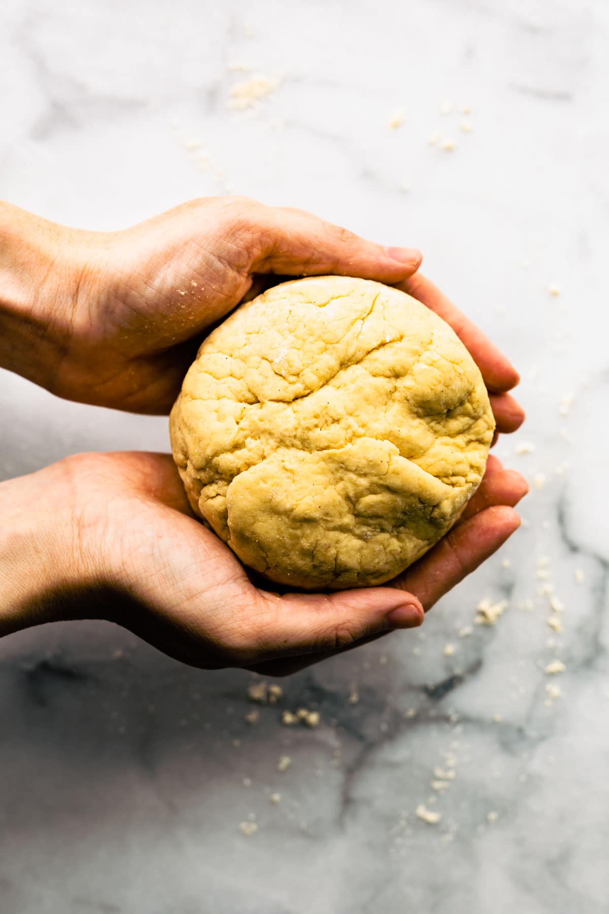 A woman's hands forming pizza dough into a ball.