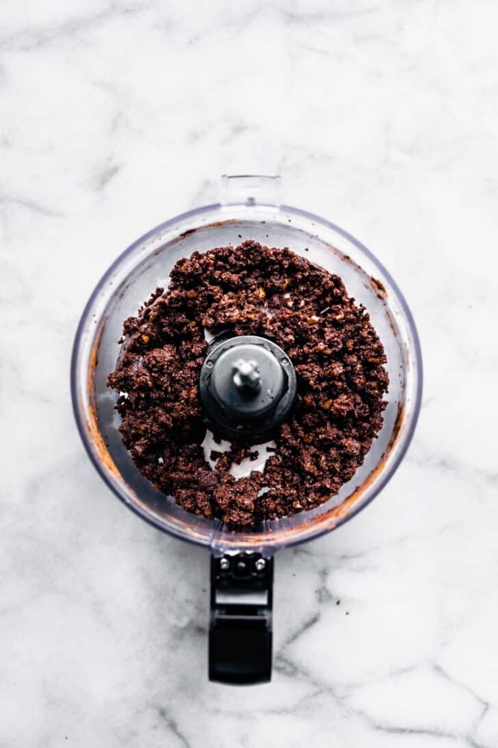 Blended chocolate nut-free protein balls batter in the bowl of a food processor.