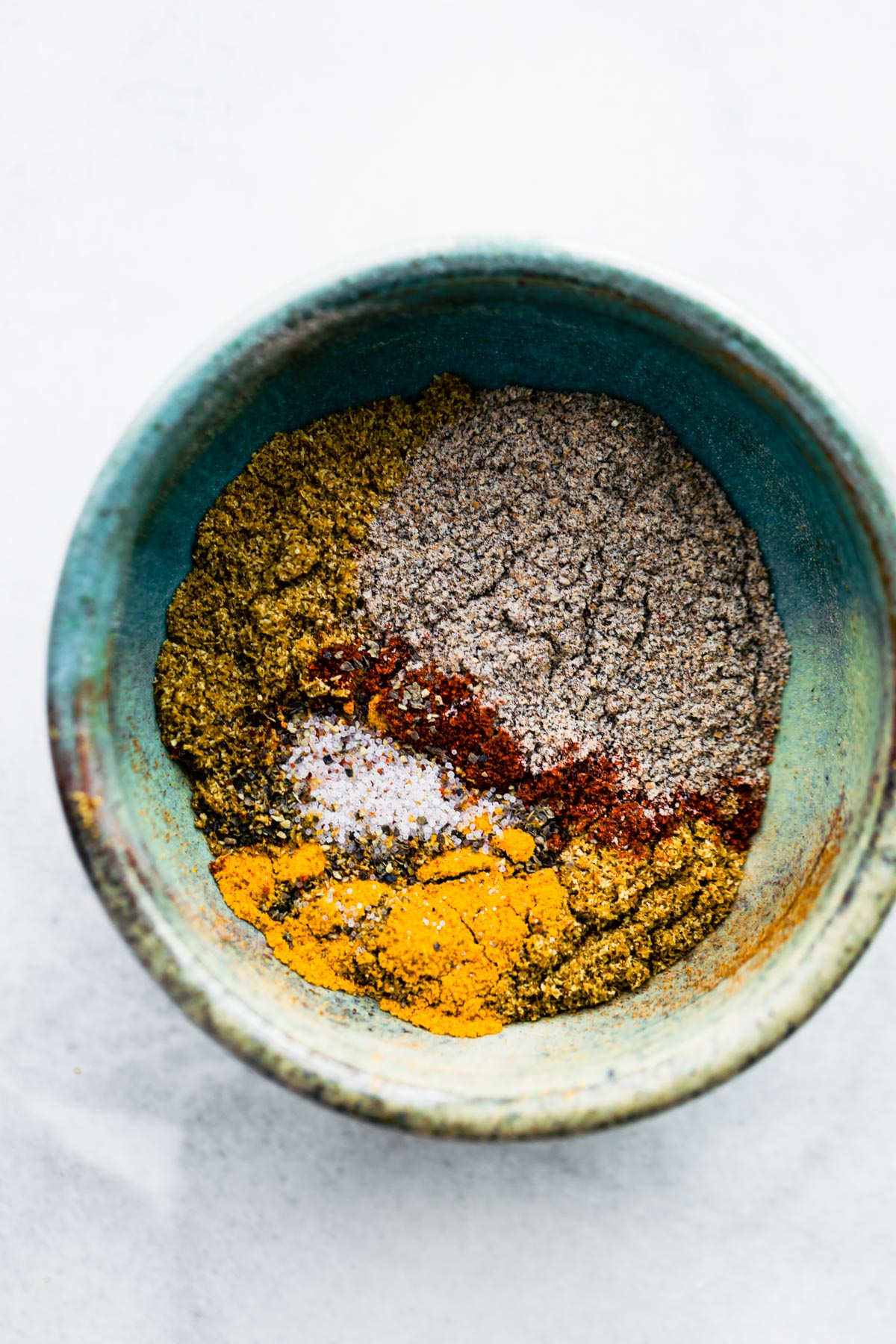 Ground spices in a blue-green ceramic bowl for roasted chicken shawarma recipe.