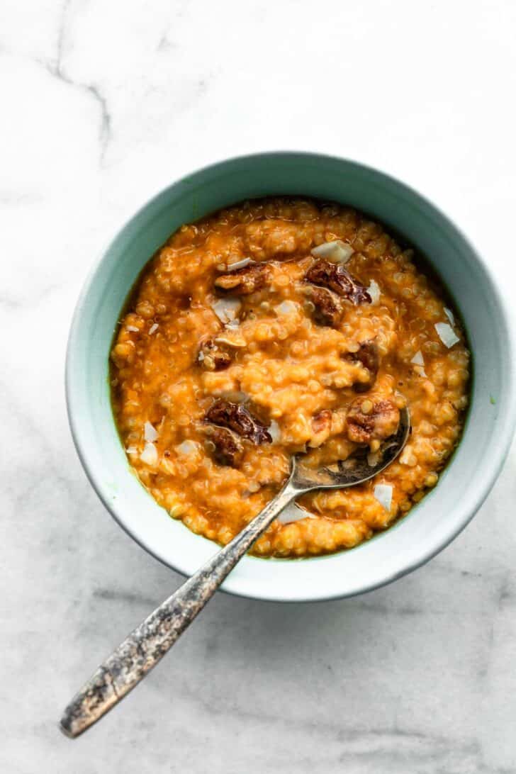 Pumpkin Quinoa breakfast porridge in blue bowl with silver spoon scooping into it