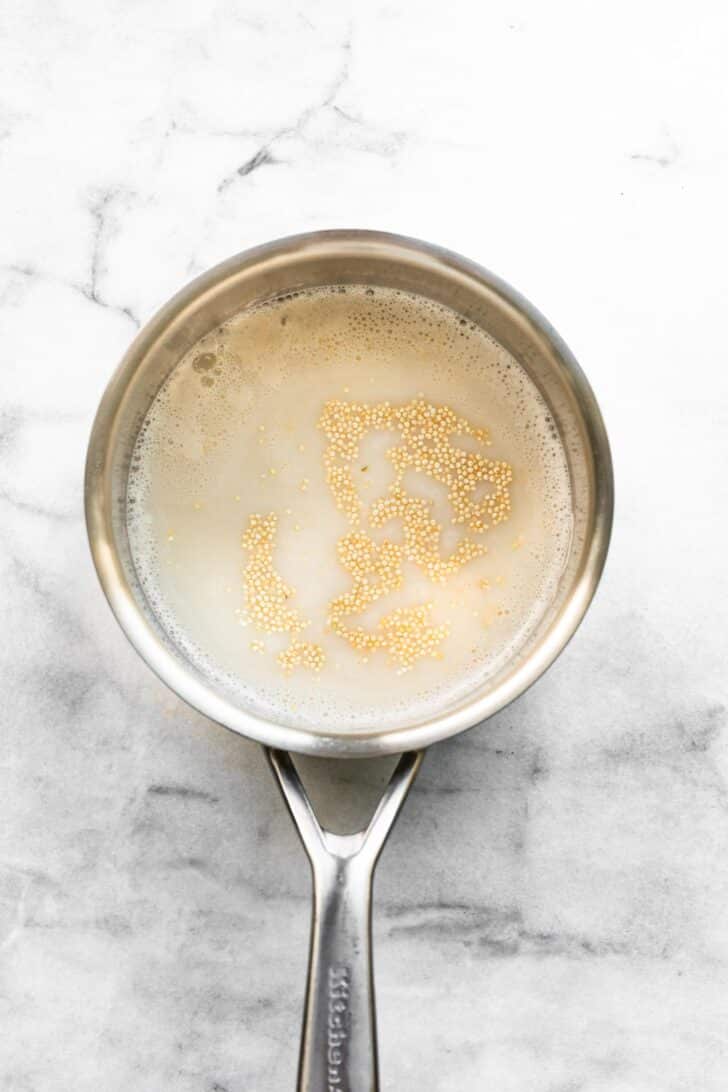 Quinoa simmering in almond milk in saucepan, step one of pumpkin porridge.