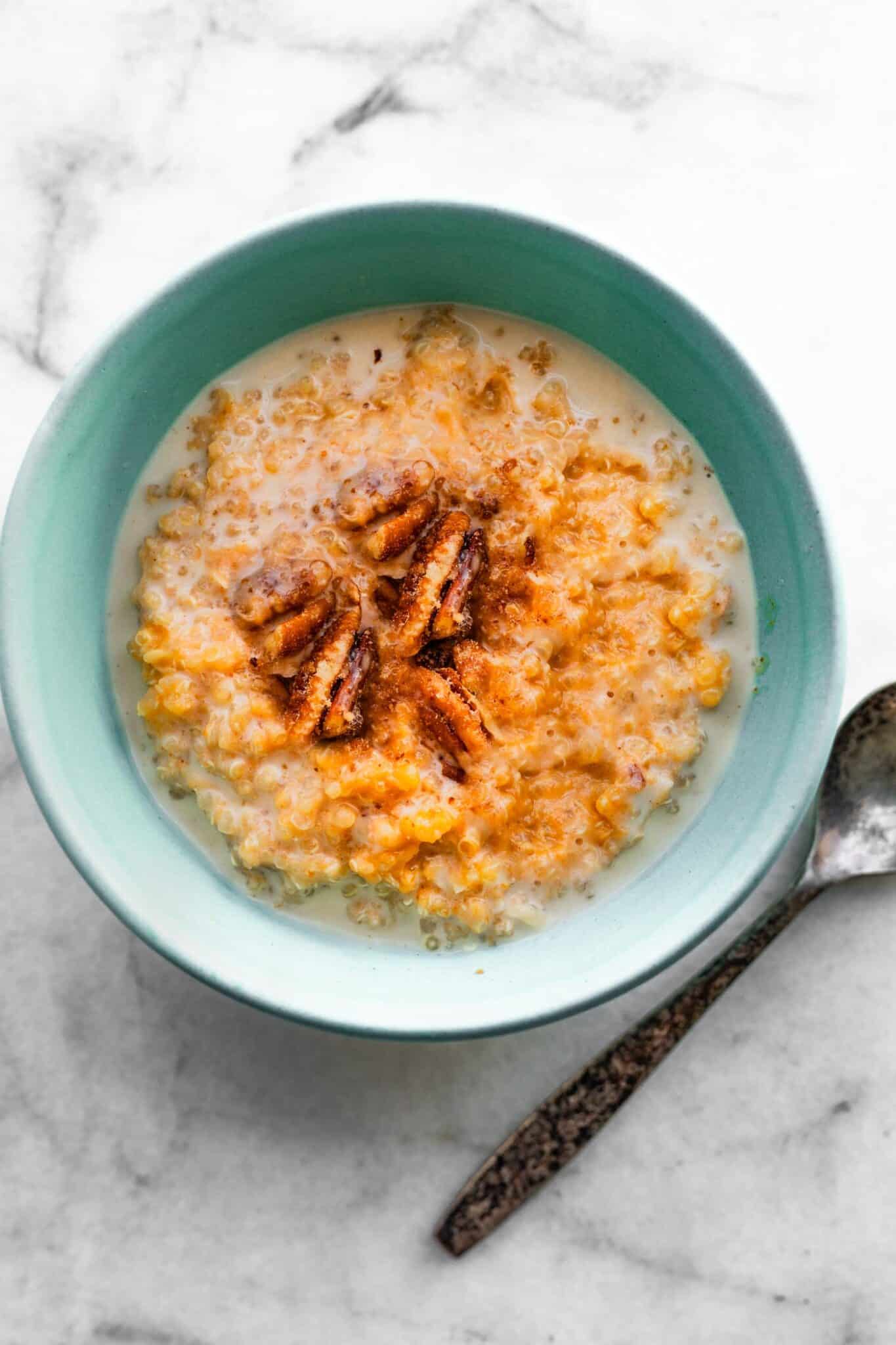 Pumpkin Quinoa breakfast porridge in blue bowl with silver spoon beside it