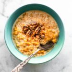 Creamy Pumpkin Quinoa breakfast porridge in blue bowl with silver spoon.