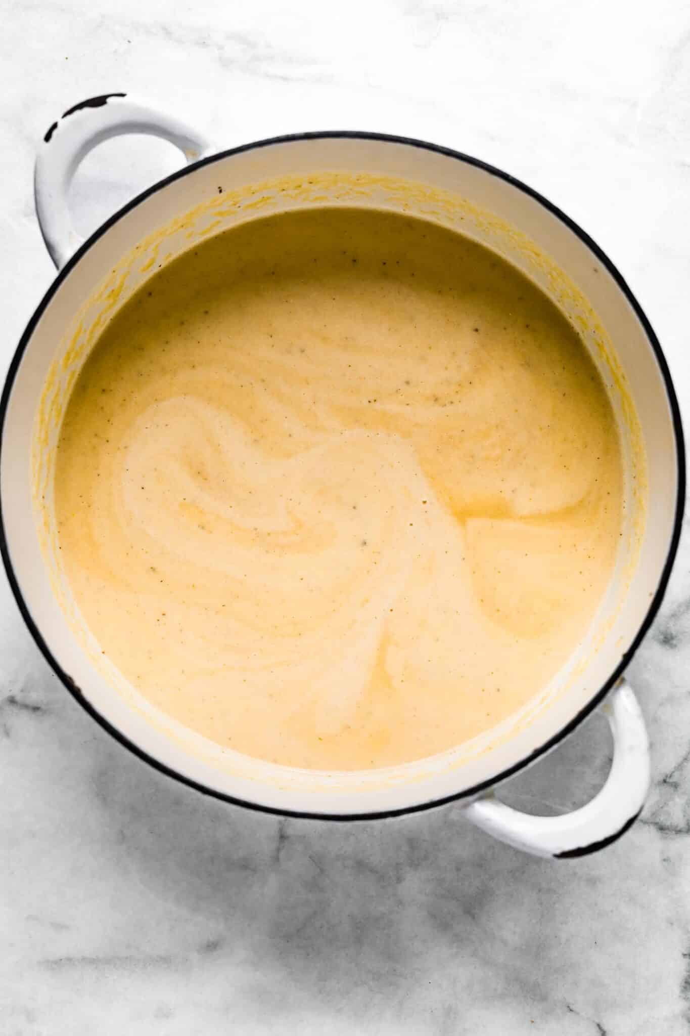 Creamy cauliflower soup in a white soup pot.