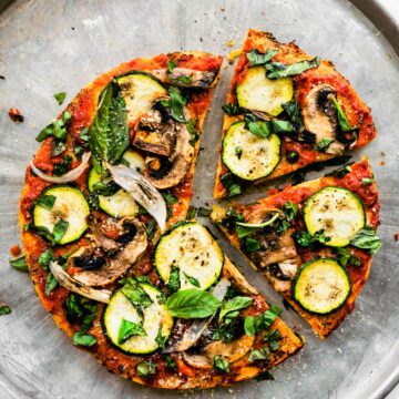 Overhead shot of finished Socca pizza with mushrooms and zucchinis.
