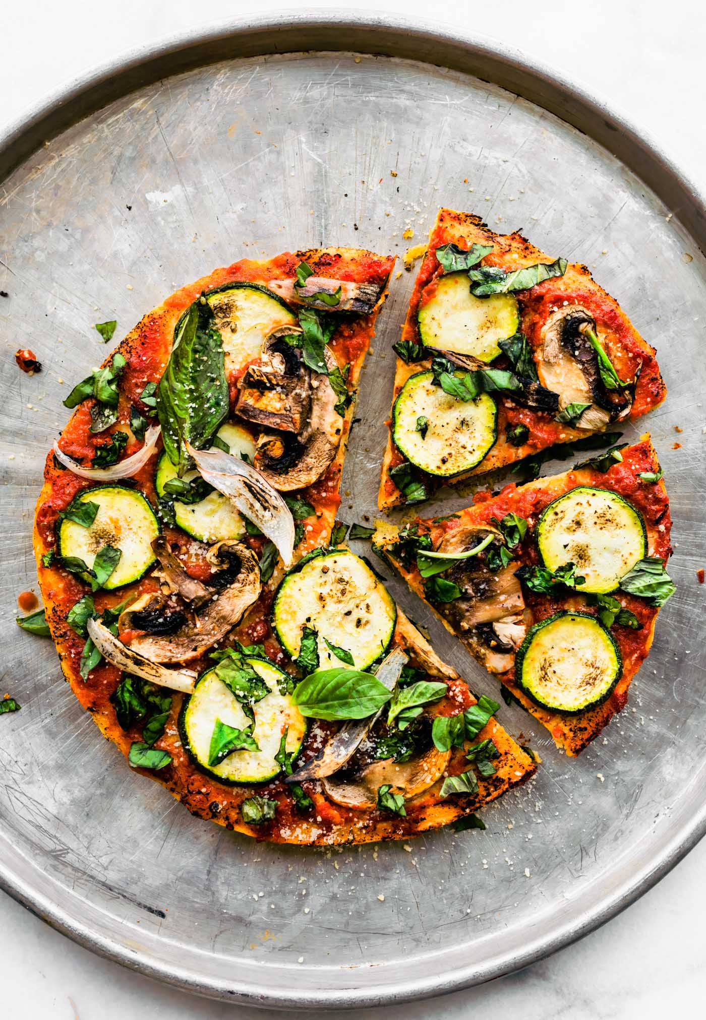 Overhead shot of finished Socca pizza with mushrooms and zucchinis.