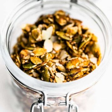 A glass jar filled with granola made from seeds.