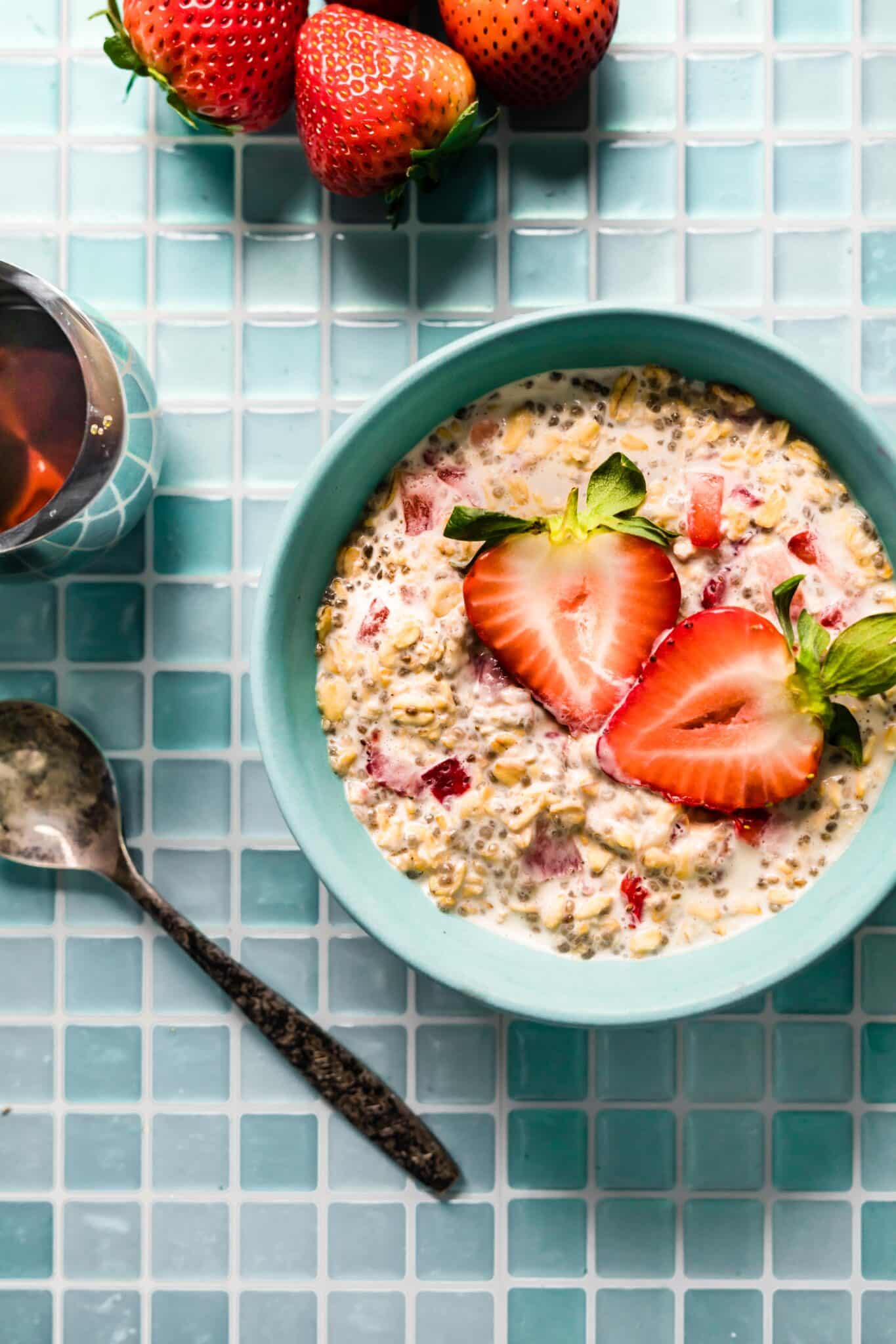 Overhead photo of strawberry overnight oats in a blue bowl topped with fresh strawberries.