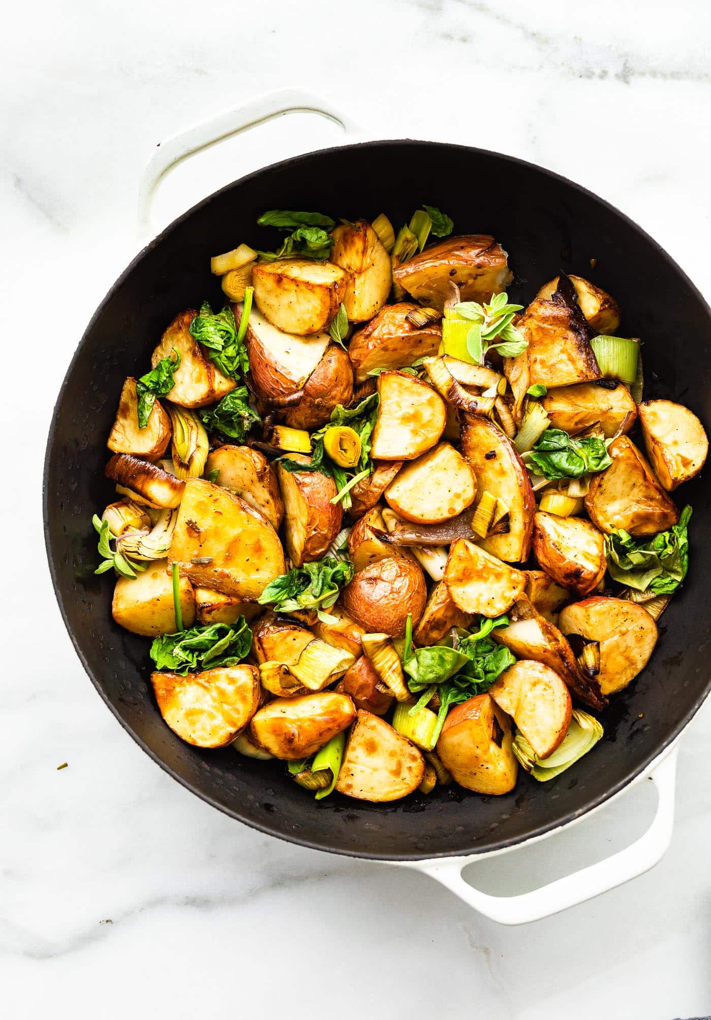 a skillet with roasted leeks and potatoes with onions