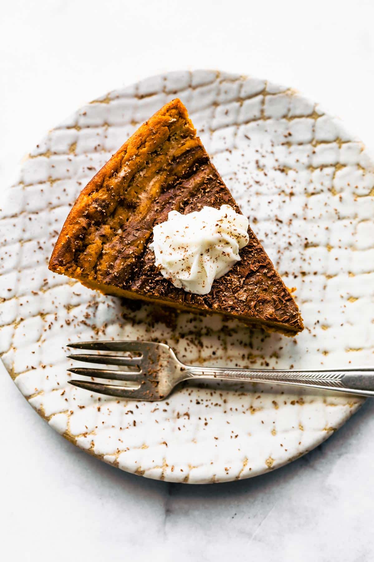 Overhead photo of a slice of gluten free chocolate pumpkin pie topped with whipped cream.
