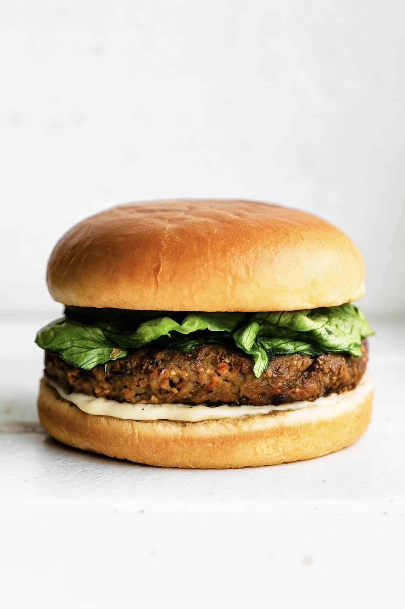 Lettuce, a veggie burger and sauce layered between a gluten free hamburger bun.