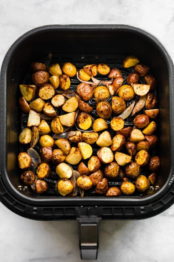 Crispy roasted baby potatoes in the air fryer basket, lightly browned.