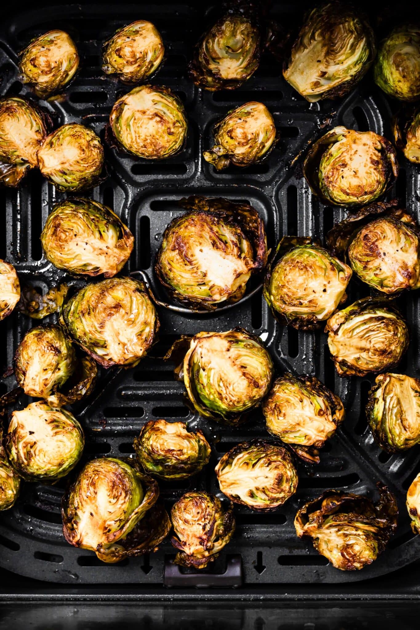 close up of crispy balsamic Brussels sprouts in air fryer basket.
