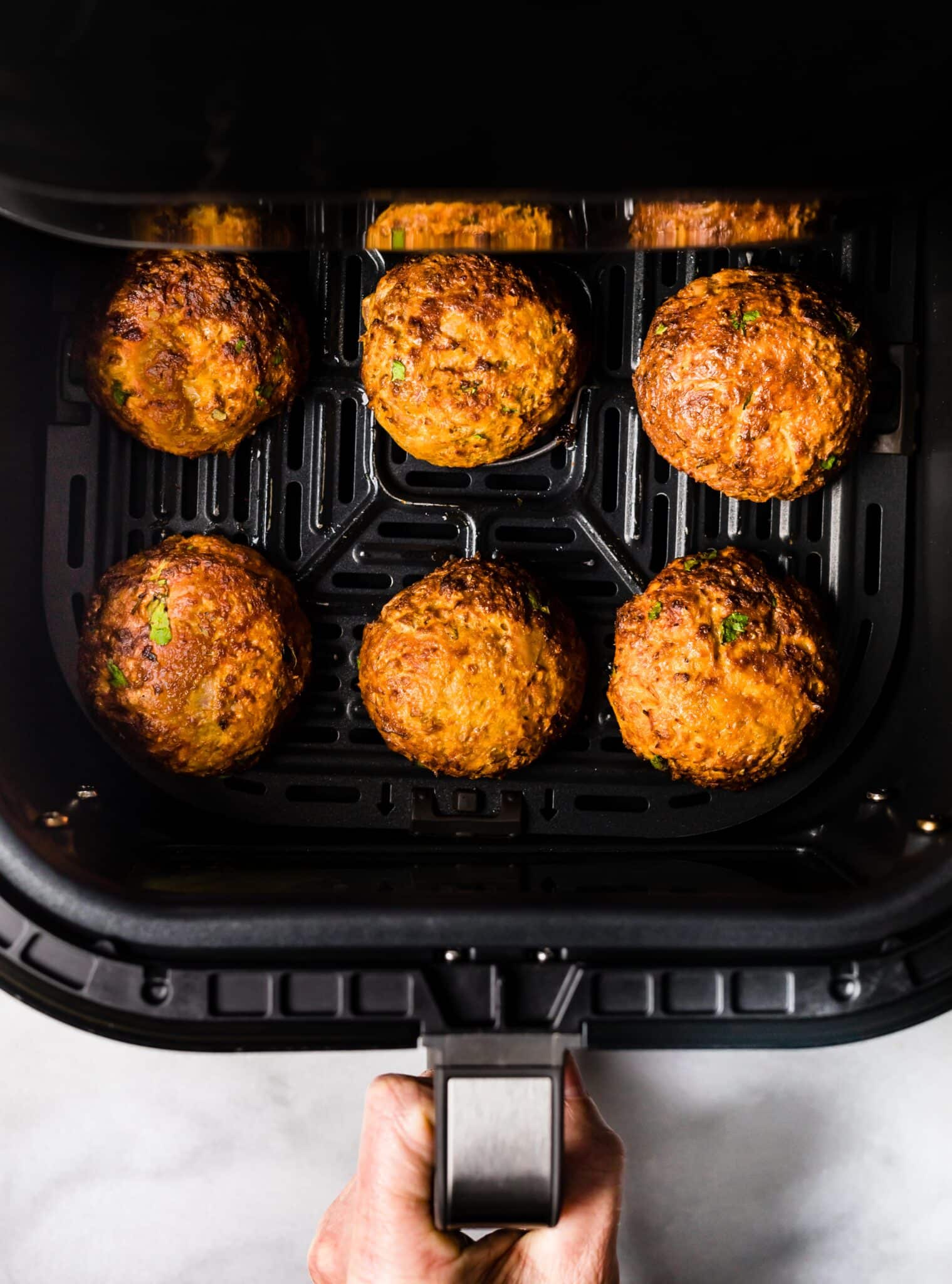 Overhead photo of air fried tuna patties in a black air fryer.