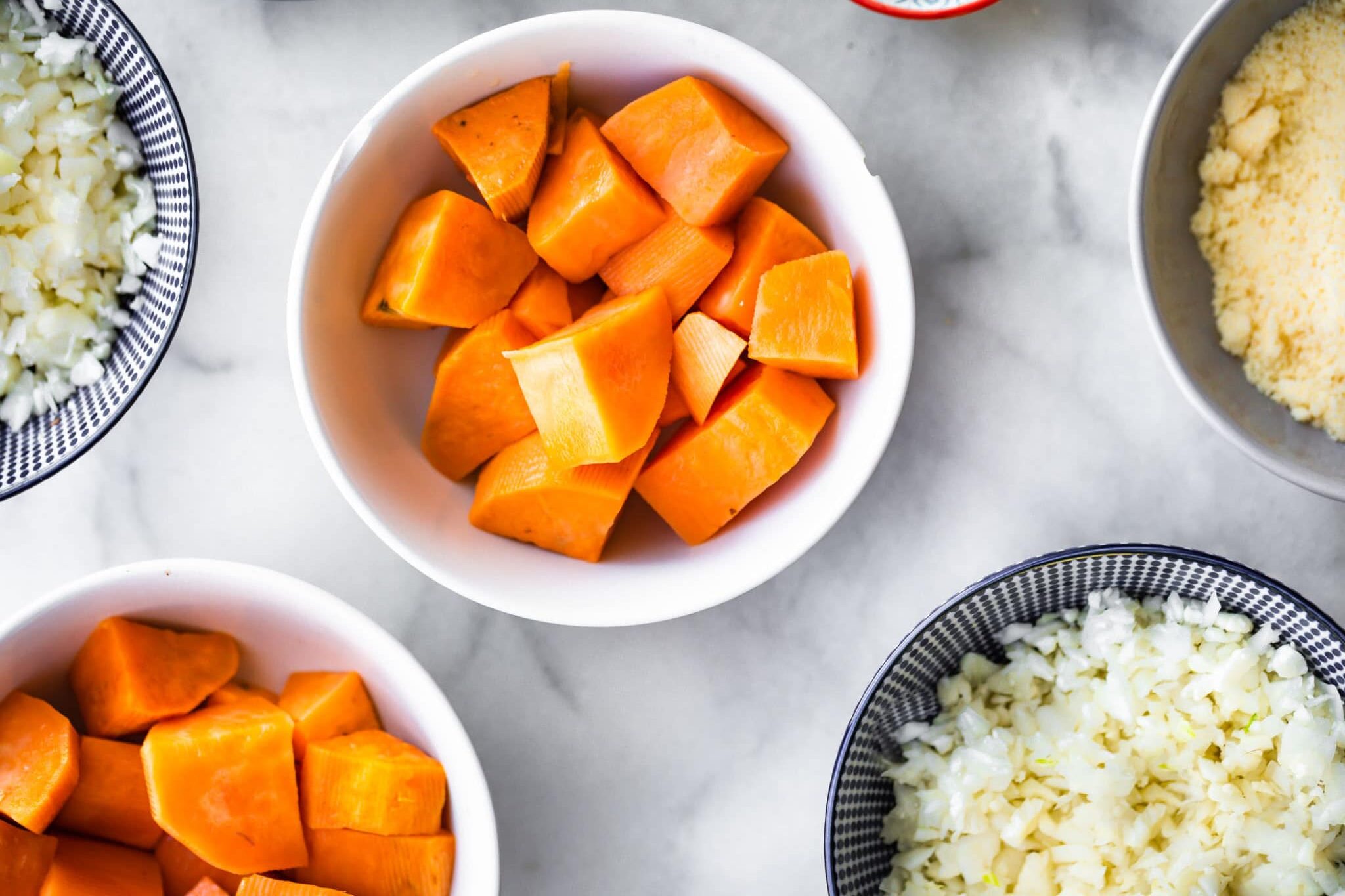sweet potatoes, reiced cauliflower, and ingredients for sweet potato tots in mixing bowls