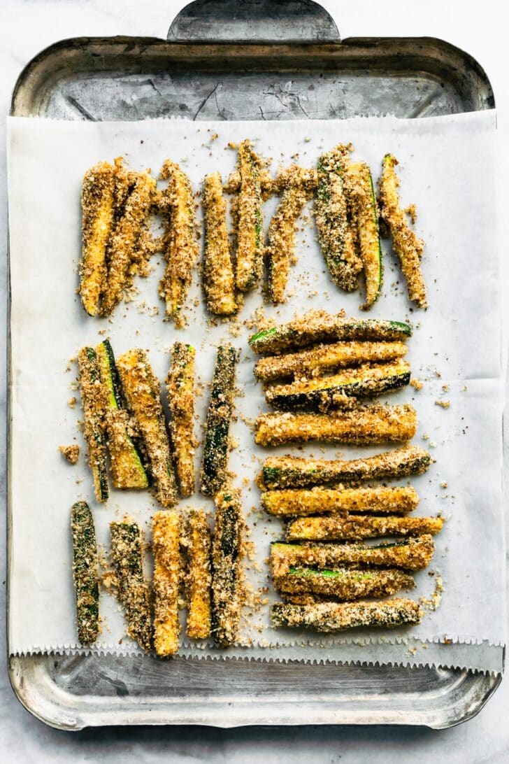 Breaded zucchini fries on a baking sheet.