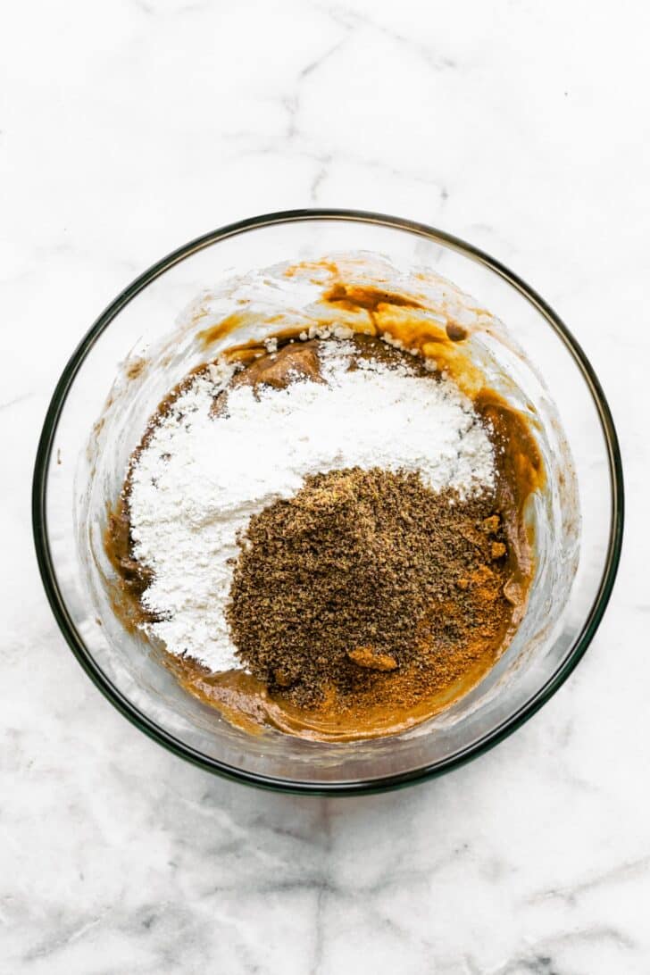 Overhead photo of tapioca flour, ground flaxseed on top of wet ingredients in a bowl.