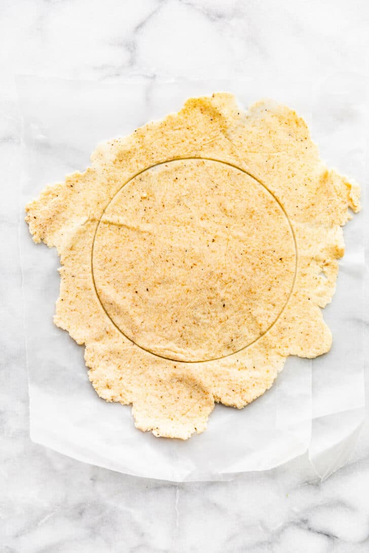 A circle cut into a slab of almond flour tortilla dough to form a tortilla.