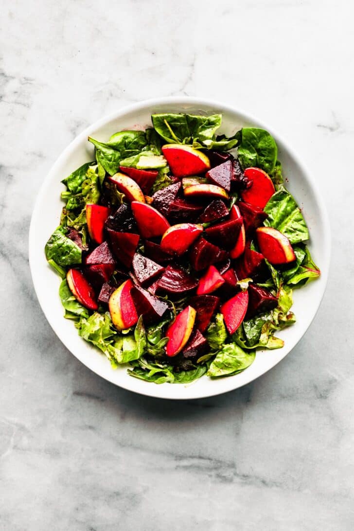 chopped apple and marinated beet salad in a white bowl