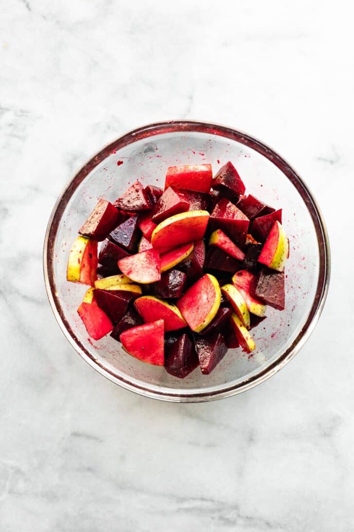 chopped apple and marinated beets in a clear bowl