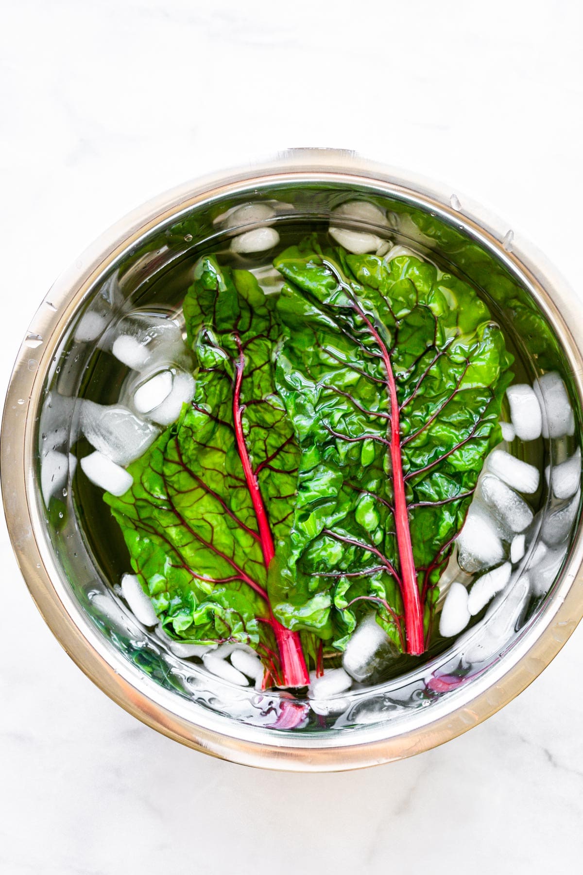 overhead image: Rainbow chard leaves in an ice water bath