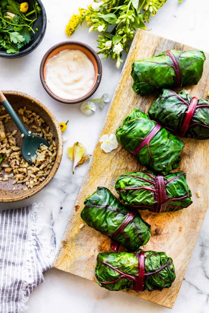 overhead photo: 6 healthy salad wraps on wooden serving board next to bowl of the filling