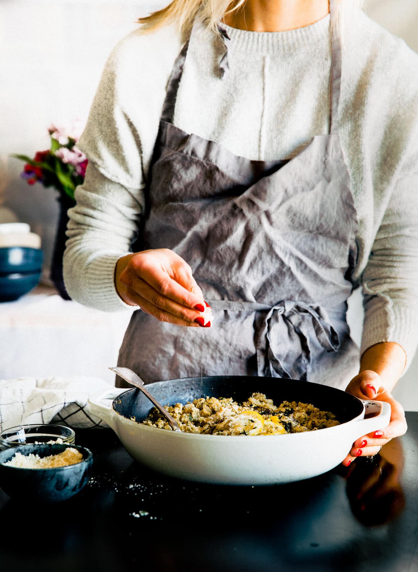 woman making risotto style veggie rice in skillet on stove top