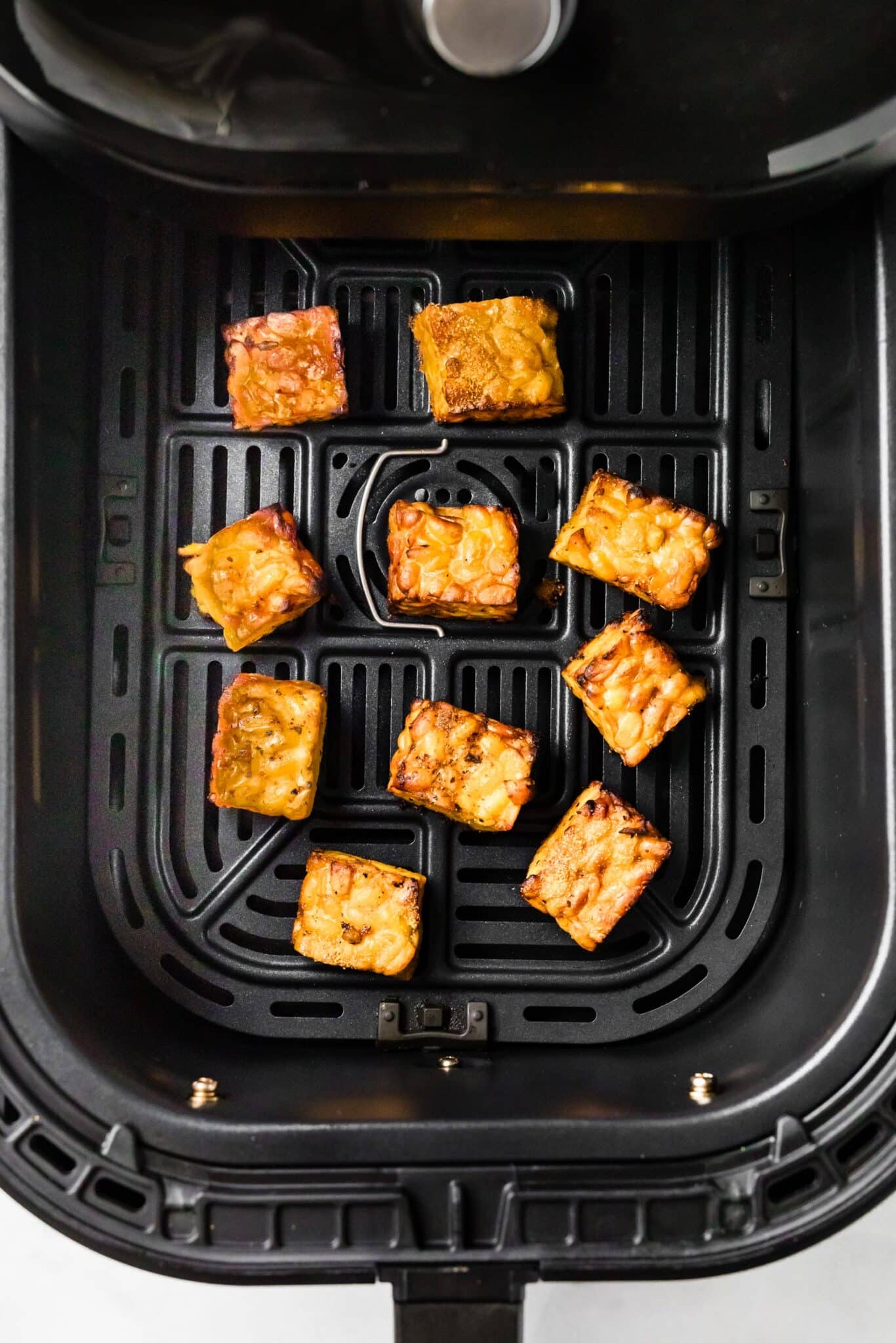 Ten cubes of cooked BBQ tempeh in an air-fryer basket