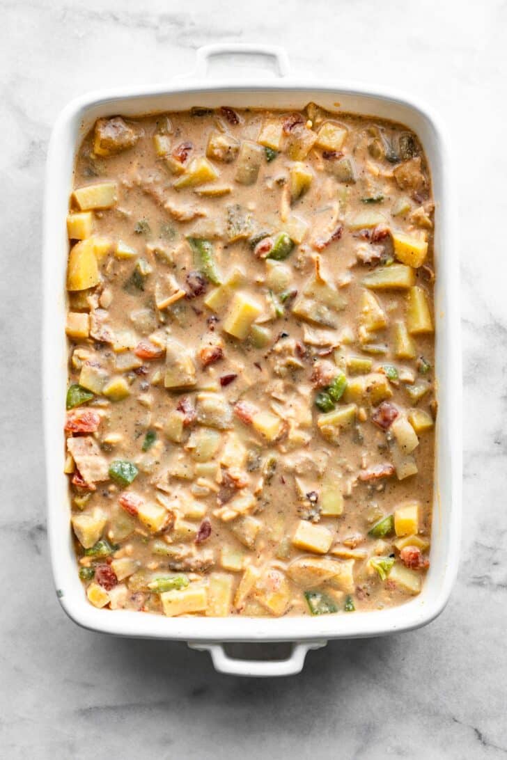 Rectangular baking dish filled with the uncooked breakfast casserole mixture.
