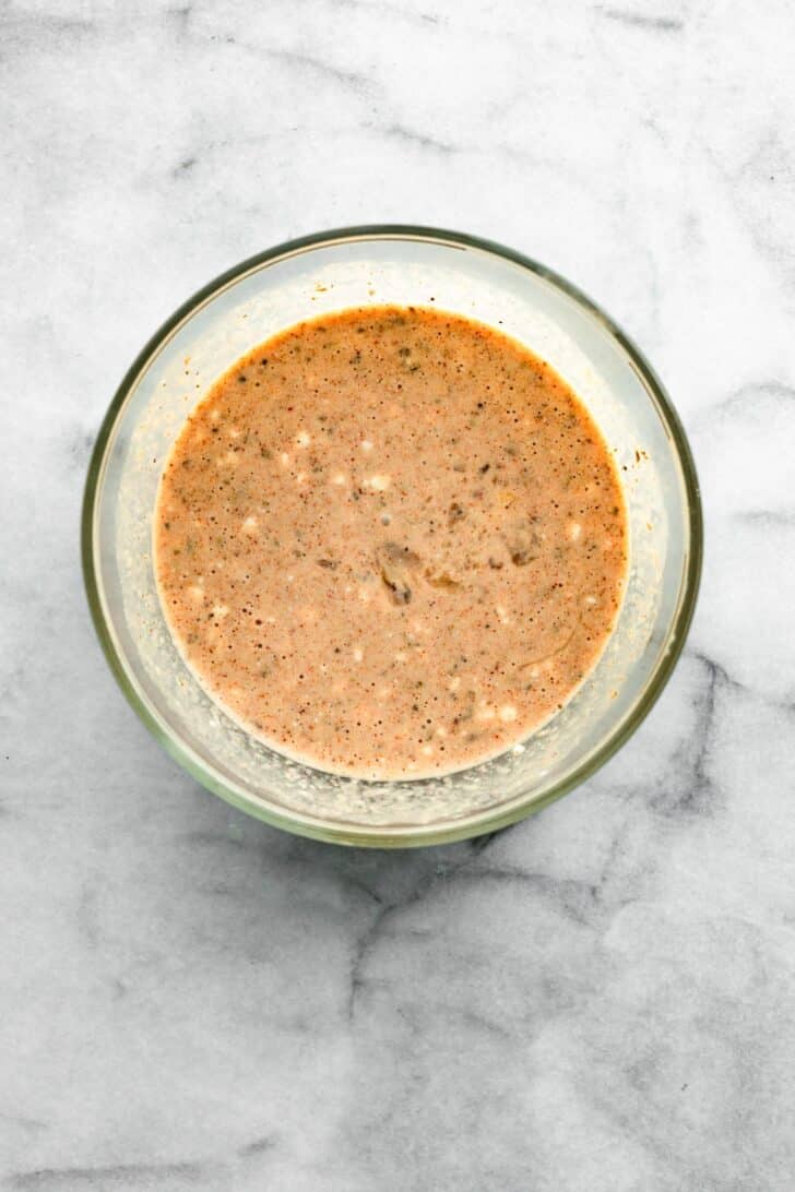 Glass bowl showing seasoned egg and cottage cheese mixture for casserole