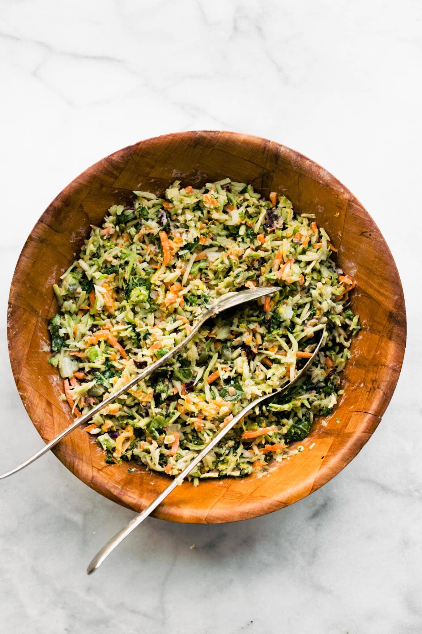Overhead photo of a healthy broccoli slaw recipe in a wooden bowl with spoons.