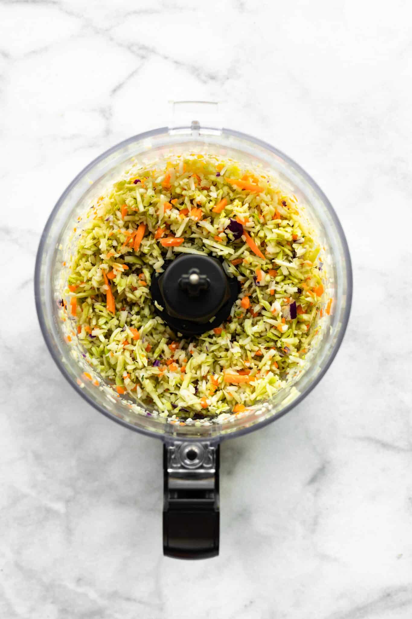 Overhead photo of broccoli slaw in a food processor.