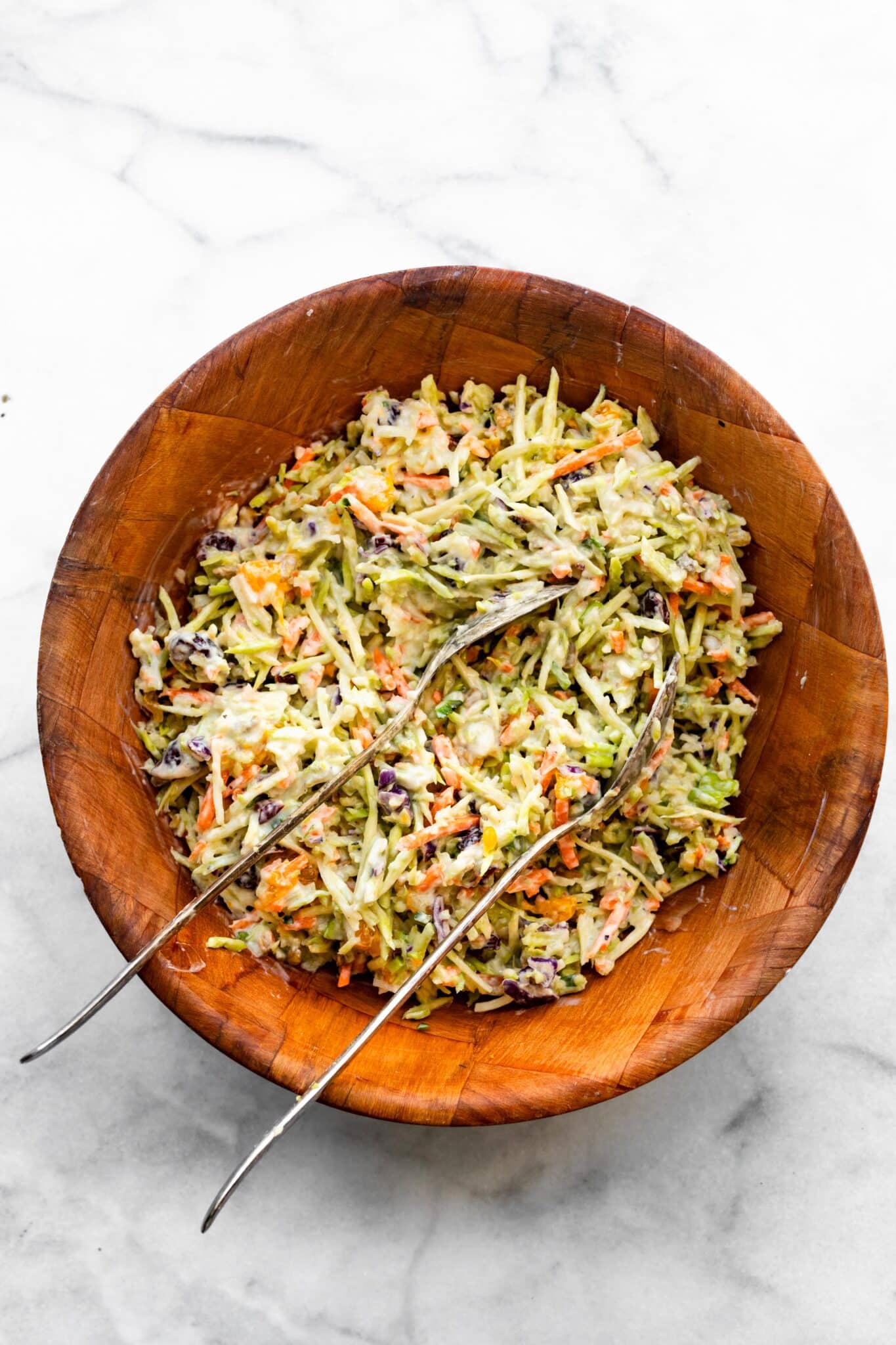 Overhead photo of two spoons mixing a broccoli slaw recipe.