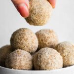 woman's fingers picking up a caramel snickerdoodle protein ball from a bowl