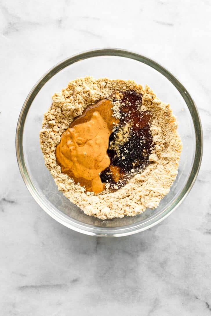 almond butter, maple syrup,protein powder, and spices in a clear bowl.