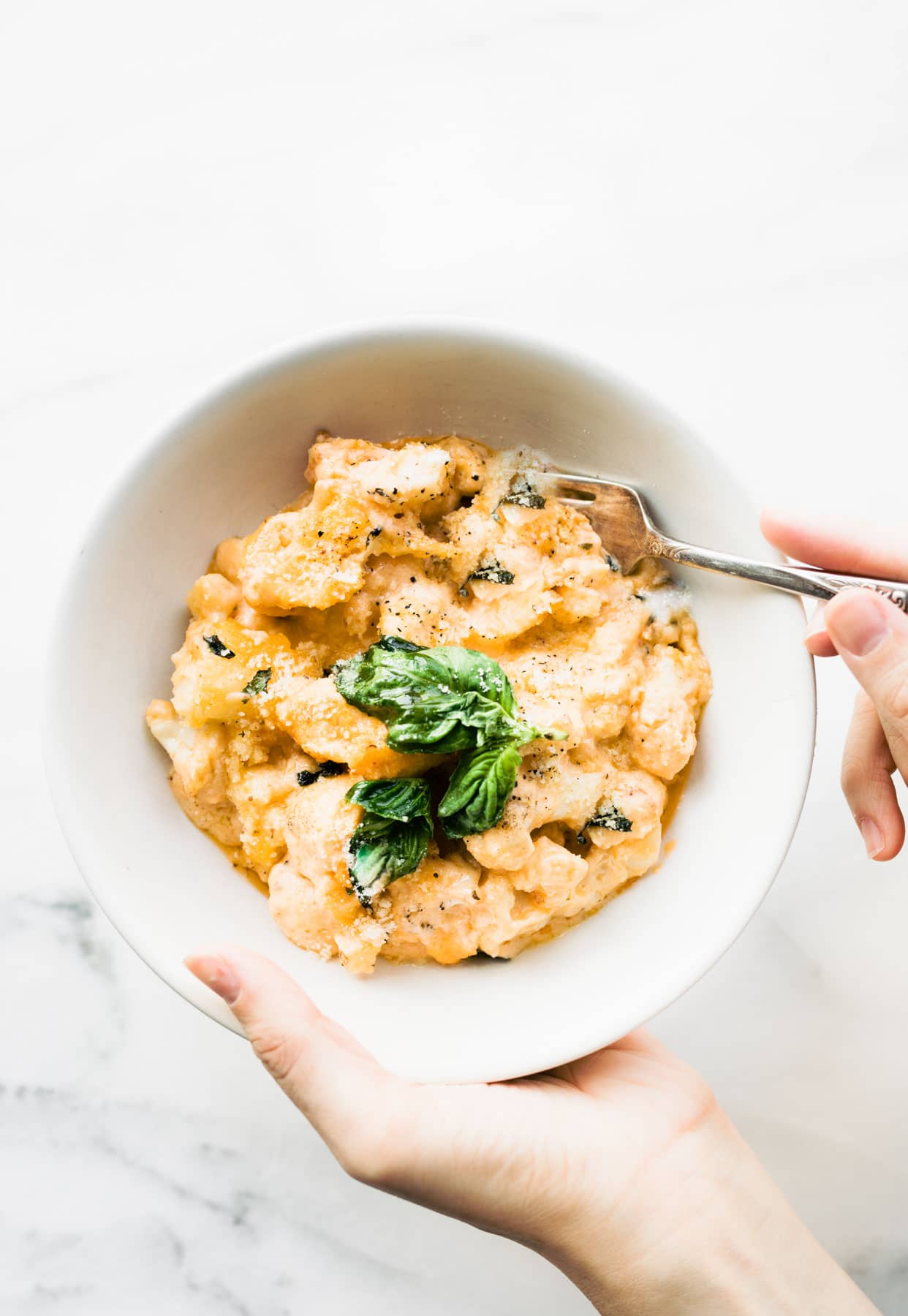 woman's hands holding bowl of homemade gluten free mac and cheese
