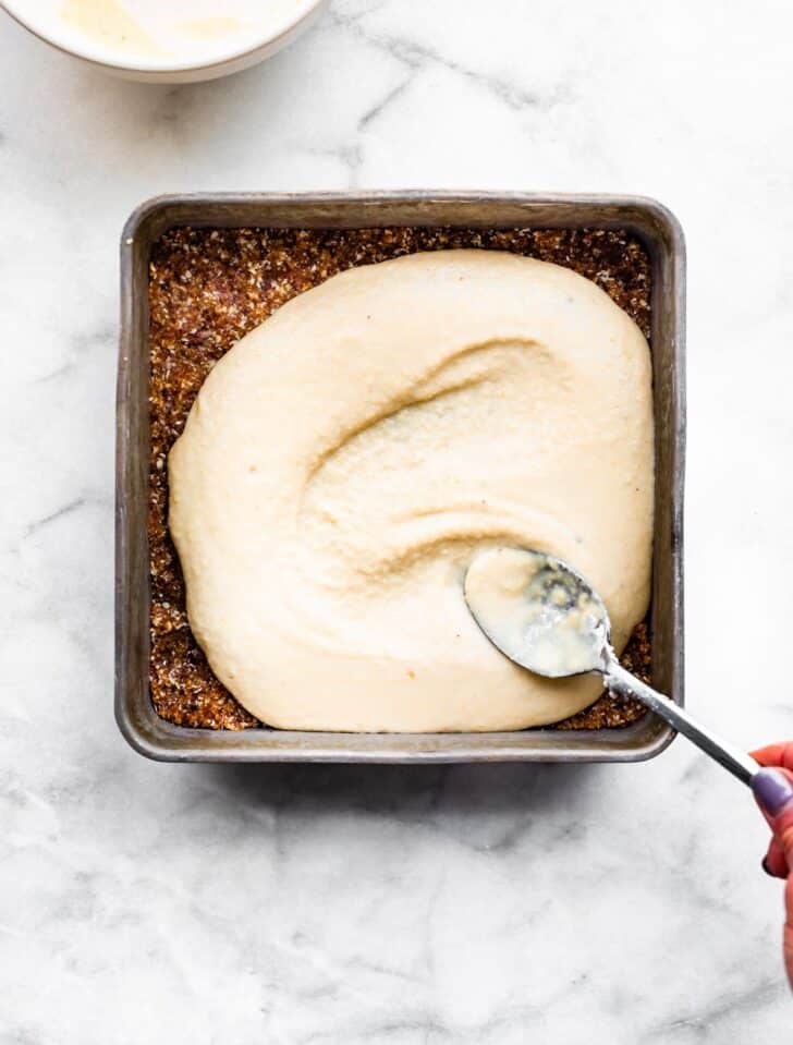 dairy free Cheesecake batter and base being spread out into a pan.