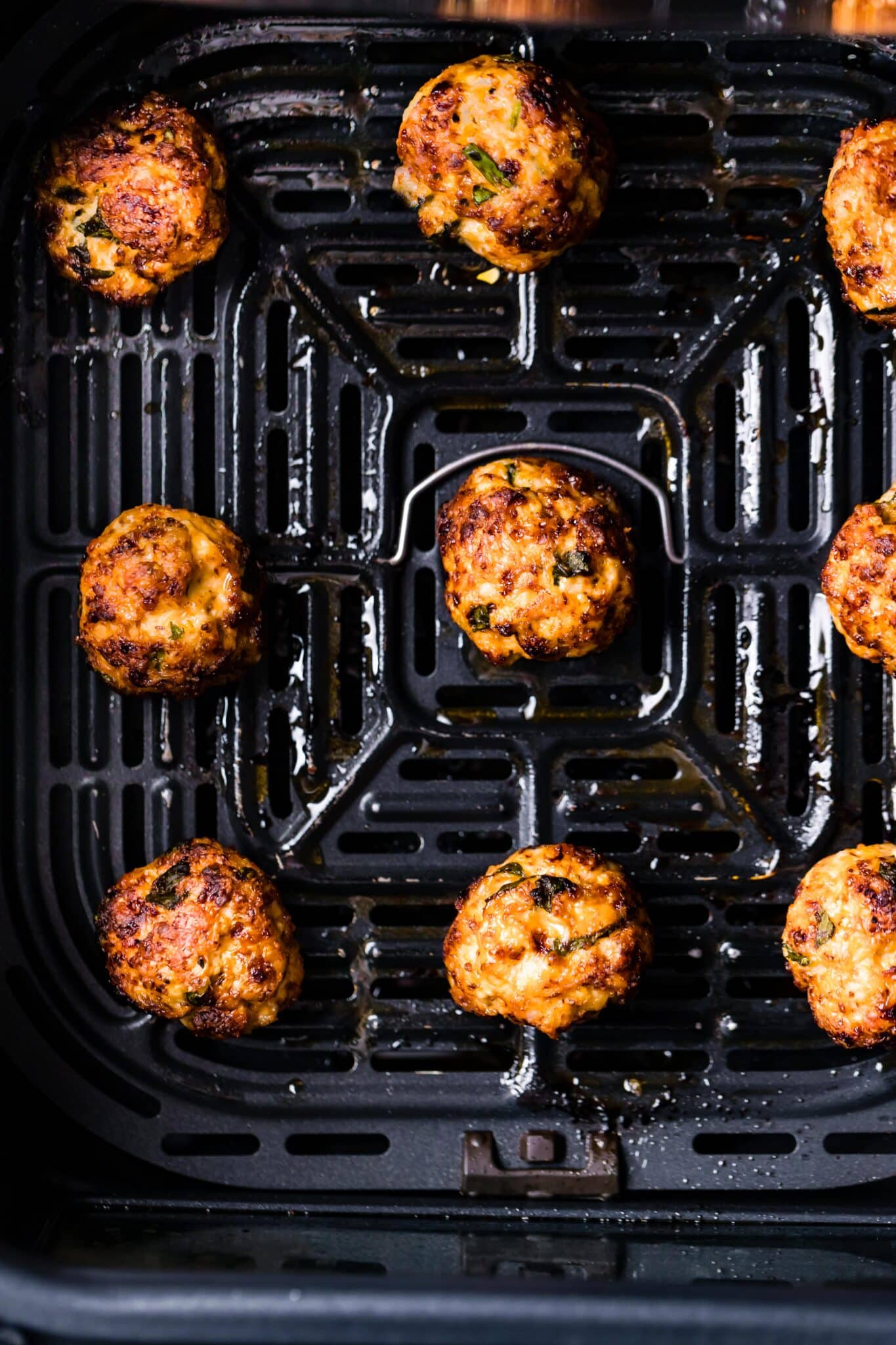 Overhead photo of air fried chicken meatballs in an air fryer basket.