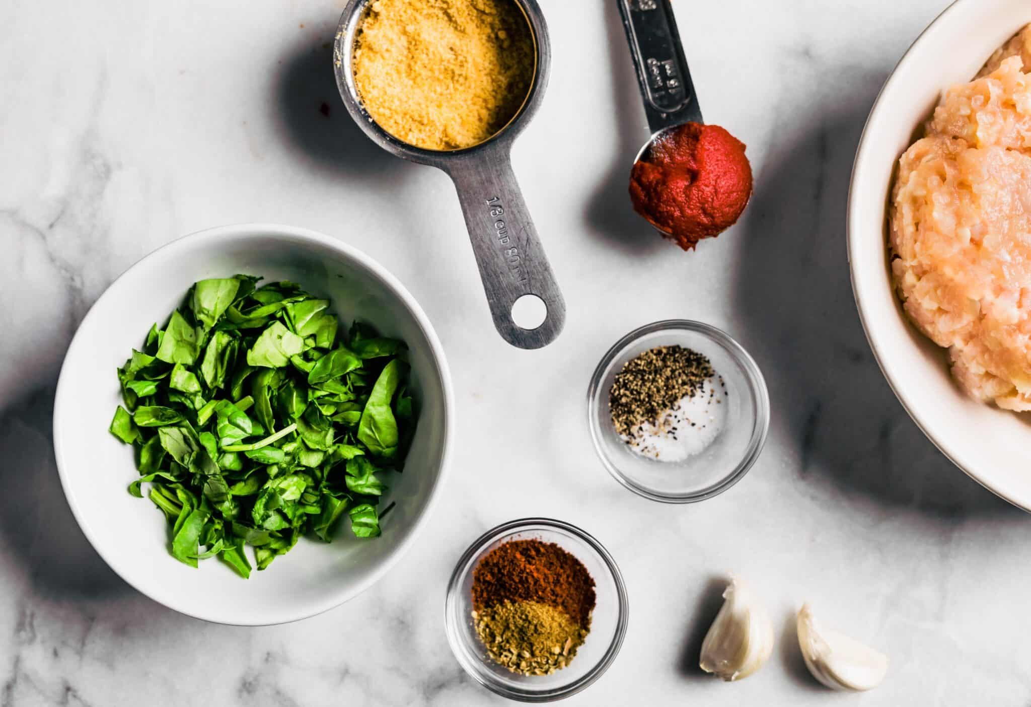 Ingredients for homemade gluten free meatballs on a marble countertop.