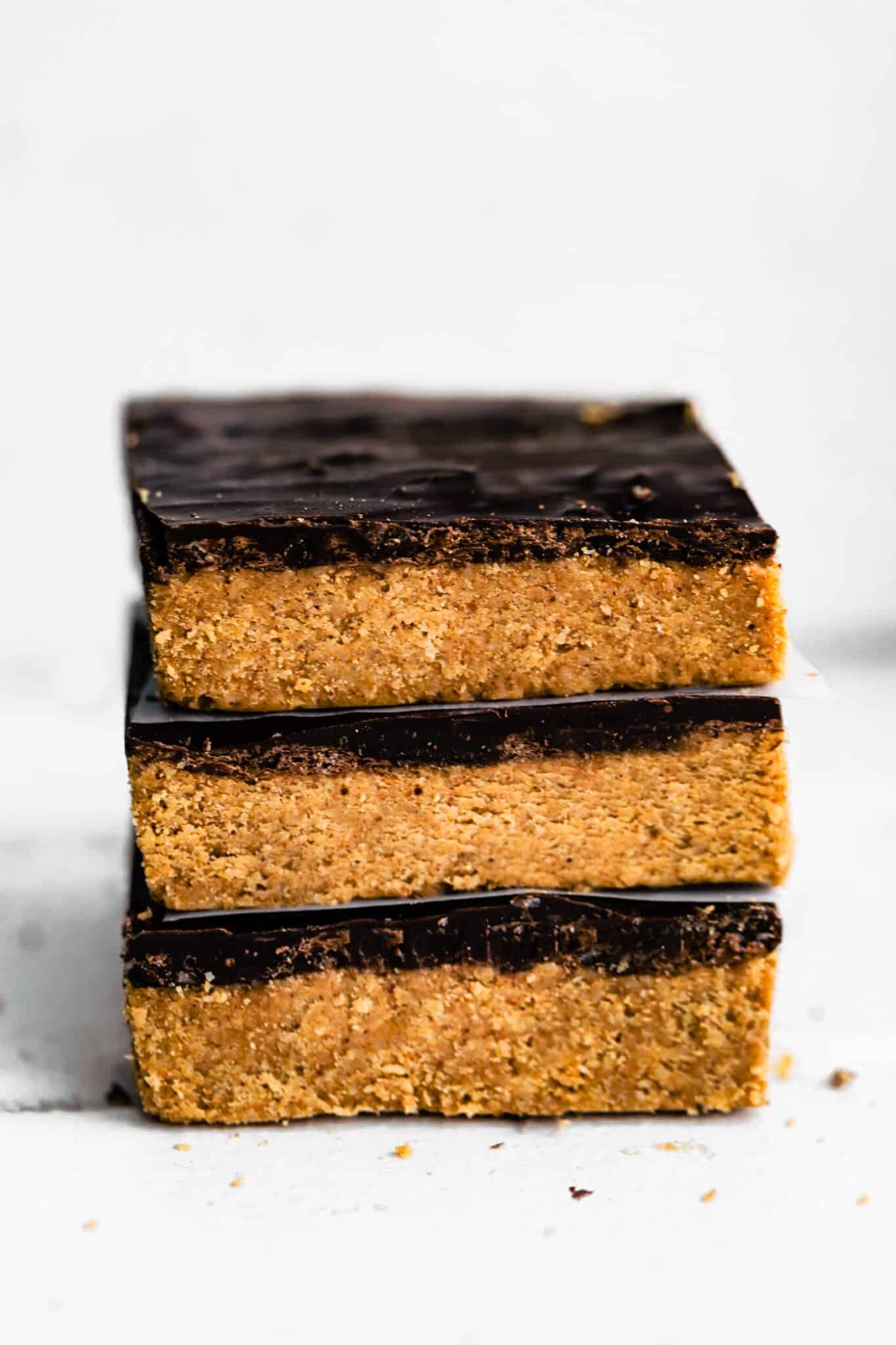 Three no bake chocolate almond flour bars stacked on a white countertop.