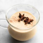 A glass mug filled with homemade dairy free eggnog topped with star anise.