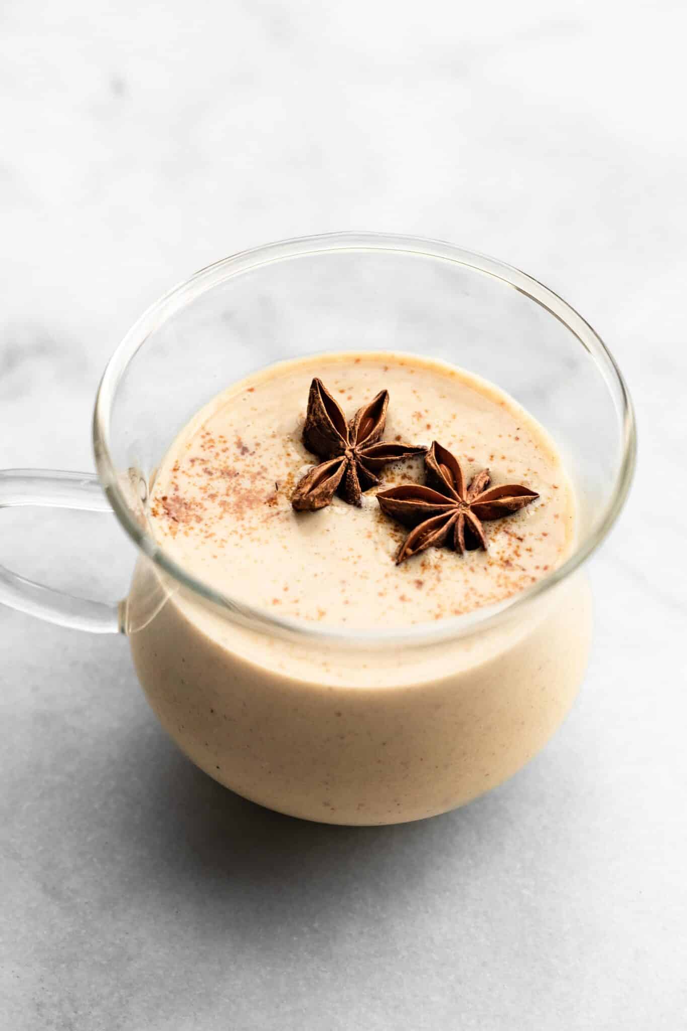 A glass mug filled with homemade dairy free eggnog topped with star anise.