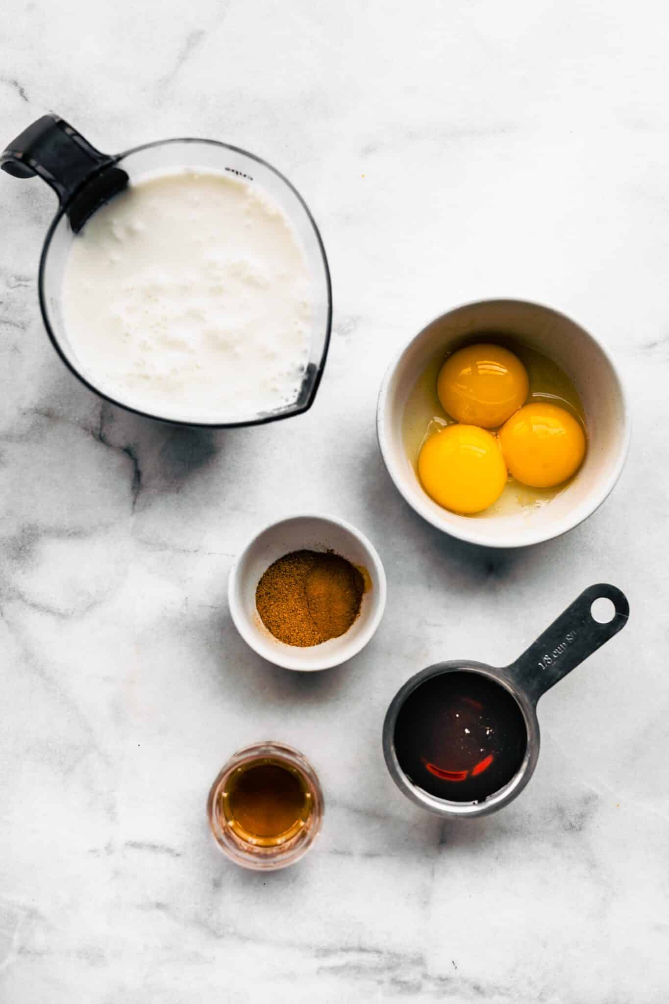 Ingredients for homemade dairy free eggnog on a white marble countertop.