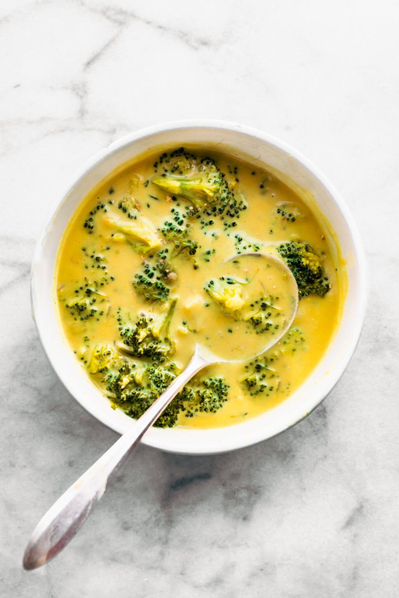 Dairy free broccoli cheese soup in a white bowl with a spoon in it.